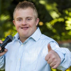 Man with microphone giving thumbs up.