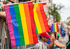 Pride flags being held over a crowd barrier at a Pride Parade