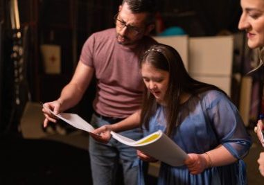 Young woman with down syndrome practicing her lines with her colleagues before a performance